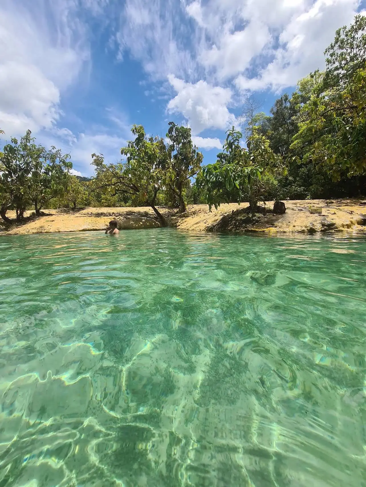 Человек купается в прозрачной изумрудной воде источника, Краби